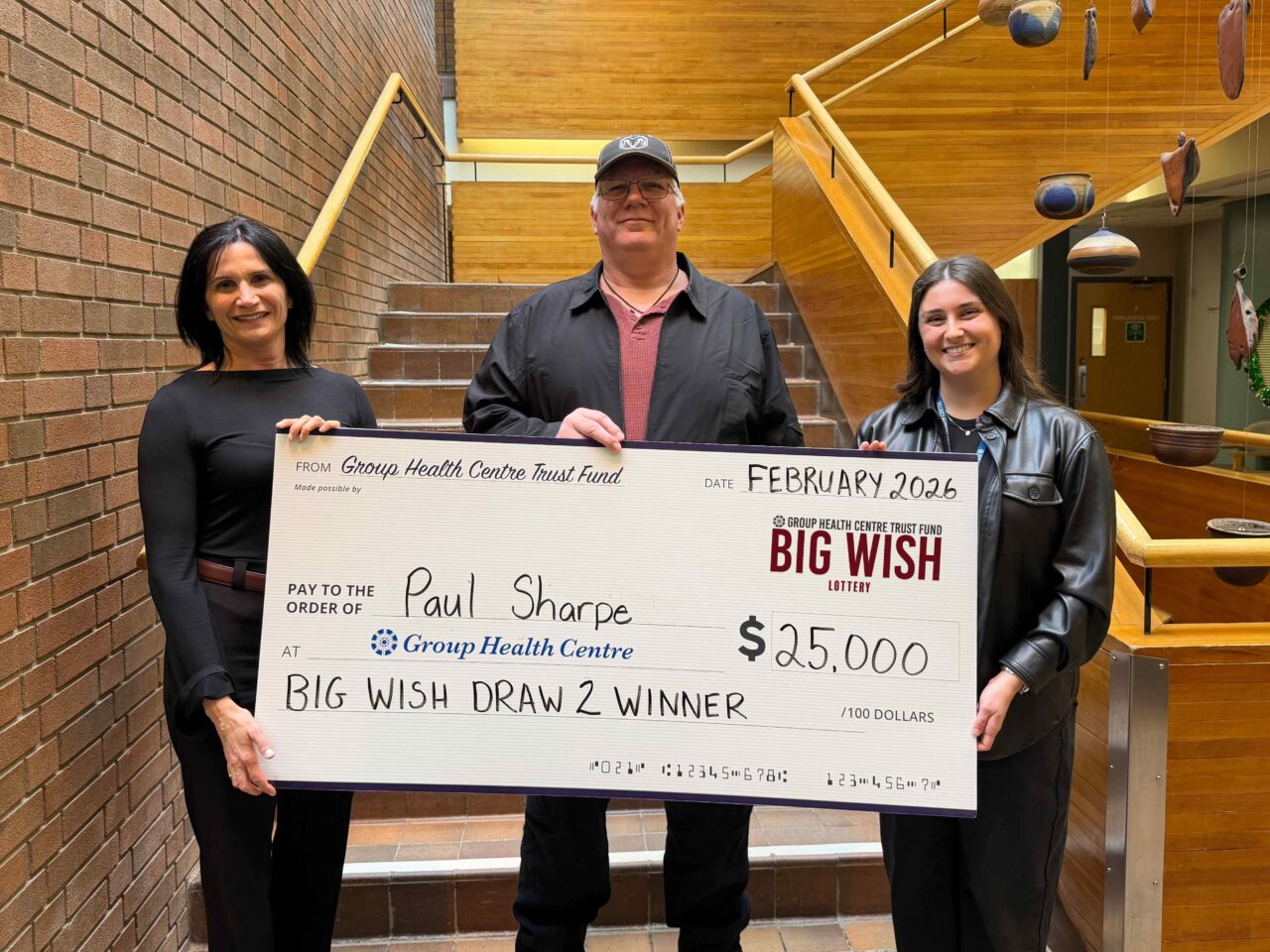 Group Health Centre CEO, Lil Silvano (left) and Trust Fund Coordinator, Amelia Stuetz (right) with winner of draw 2, Paul Sharpe holding a cheque for $25,000
