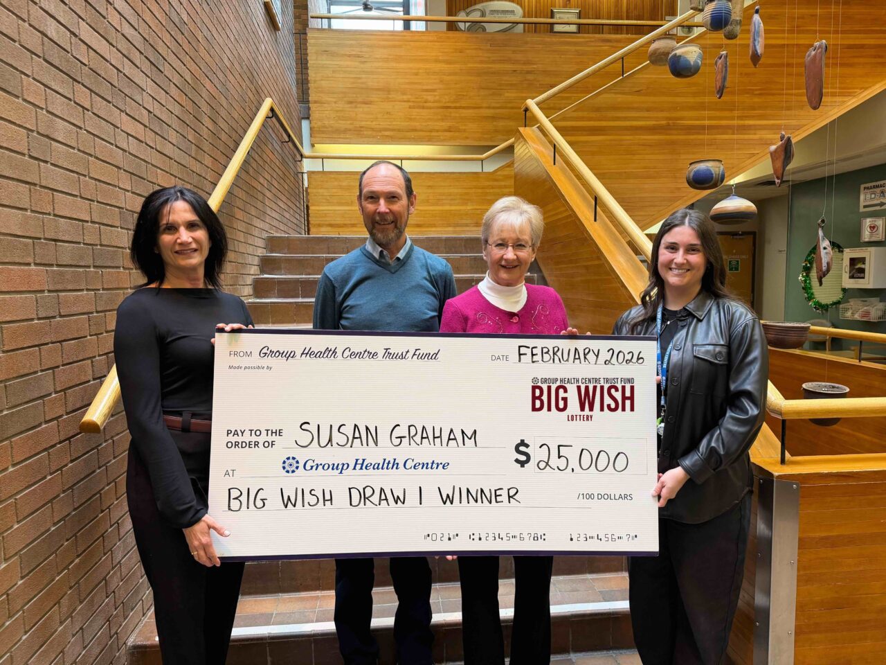 Group Health Centre CEO, Lil Silvano (left) and Trust Fund Coordinator, Amelia Stuetz (right) with winner of draw 1, Susan Graham, and husband, Cliff holding cheque for $25,000